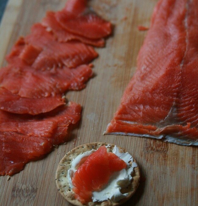 Sliced salmon on a wooden cutting board.